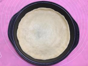 用手将饼皮压成和披萨盘一样大小圆形。