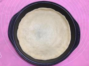 用手将饼皮压成和披萨盘一样大小圆形。