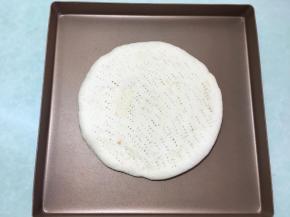 两个都做好后取一个烤好的披萨皮，放在烤盘里。