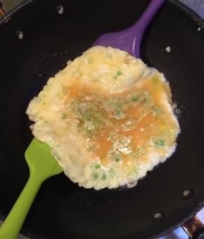 用两个刮刀，插在蛋饼的底下，抄起蛋饼，翻个，如果有破损，或者裂开不要紧，用那些稀的蛋液可以把有毛病的地方粘一起。