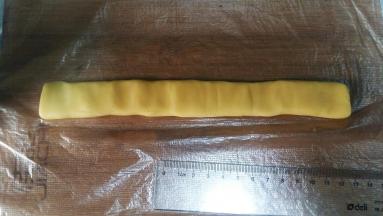 取38克原味面团，搓成21CM长条，按扁。然后放在保鲜膜或保鲜袋上；