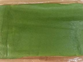 剩余的抹茶面团搓成21CM长条，套上保鲜袋擀成中间稍厚，两边薄的片状，宽度以完全包裹住步骤14的面团为准。