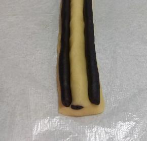 取两条11克可可长条，放在步骤10（熊猫鼻子)两侧做眼睛，轻轻把可可长条跟鼻子捏合。一定要完全贴合，要不切开会有缝隙。