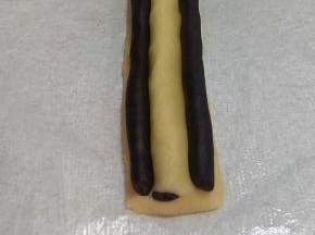 取两条11克可可长条，放在步骤10（熊猫鼻子)两侧做眼睛，轻轻把可可长条跟鼻子捏合。一定要完全贴合，要不切开会有缝隙。