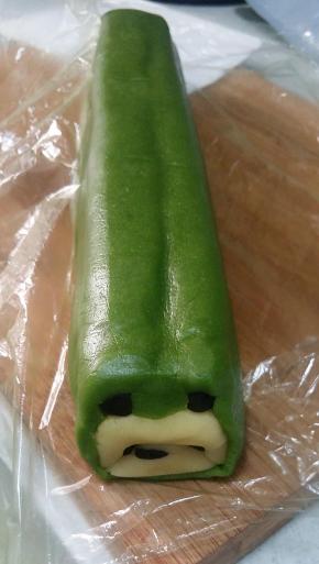 抬起一侧的抹茶面片，底部垫着保鲜袋，很容易操作。慢慢的从底部开始贴合面团，直至贴到顶部，轻轻压平。另一侧以同样的手法操作。最后将接口压平。放冰箱冷冻至硬，面团一定要冻硬，要不切起来会变形。