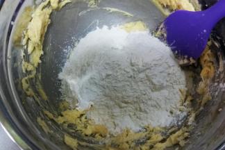 把过筛后的低粉倒入打好的黄油中，用刮刀翻拌均匀，捏成面团。