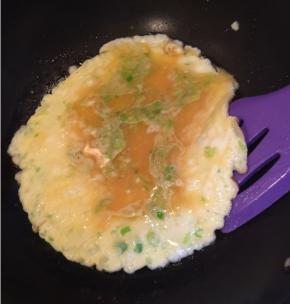 中间稀蛋液慢慢减少，用刮刀转一圈，让蛋饼脱离锅子，准备翻面。