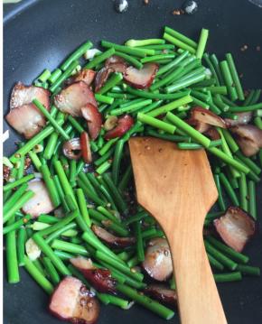  放入少量六月鲜酱油，葱花，翻炒至腊肉微微卷边