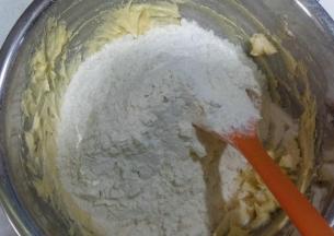 低粉过筛，倒入打发的黄油中，用刮刀翻拌均匀