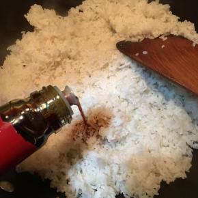 加入事先煮熟打散的米饭，淋入酱油翻炒均匀。