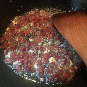 下入腊肠翻炒至表面微焦。