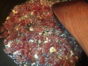 下入腊肠翻炒至表面微焦。