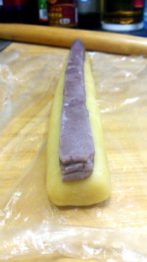 将抹茶面团切出三个1CM的长条，叠放在椭圆面团中央，用保鲜膜将两种面团压实弄平整；