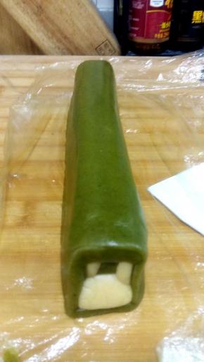 剩下的抹茶面团包裹住步骤9的面团，用保鲜膜把面团压实弄平，以免烤好的饼干出现空洞，面团放冷冻室30分钟，面团一定要冻硬。