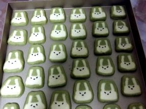 取出冷冻好的面团，切成5MM宽的薄片；放在烤盘上，取适量蜂蜜，用少许化开。然后用筷子沾水，在兔子脸上点黑芝麻。点成“八字形”会更萌哦。面团一定要冻硬再切，否则兔子会变形。如果觉得切完兔子形状不好看，没关系，把饼干放烤盘上，面稍微软点手动微整形就好；