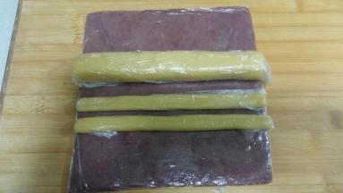 两份21克面团分别滚圆成20*20CM长条，然后按扁。
132克面团搓成20*20CM的椭圆形。
抹茶面团套上保鲜袋擀成20*20CM的正方形面片。
把上述做完的面团放冰箱冷冻5分钟，摸着面团变硬即可，不要冷冻时间太长，以免操作时断裂。
