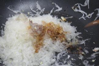 加洋葱粒、虾仁，用小火慢慢炒粉丝，将粉丝的水分炒干