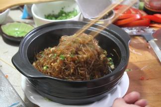 撒入葱花，捞取粉丝，起锅装入烧好的煲仔