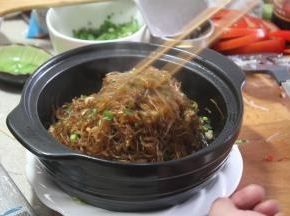 撒入葱花，捞取粉丝，起锅装入烧好的煲仔