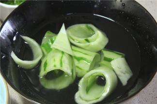 片下来的黄瓜片卷成筒状，放入冷水中浸泡一下，浸泡可以让黄瓜片的口感变的更加清脆