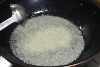 锅内倒入多一点的食用油，烧至二层油温的时候取三分之二的蒜放入锅内