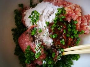 肉馅里加入盐，老抽，淀粉，耗油，料酒，黑胡椒粉，豆瓣酱，葱花，分次加入一些水，搅打上劲