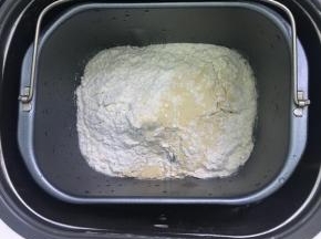 除黄油以外的所有面团材料按先液体后粉类的顺序投入面包机，启动和面程序10分钟。