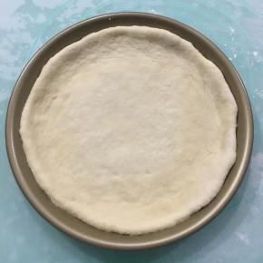 移入不粘披萨盘中，稍微整理一下，使其外边一圈比里面厚。