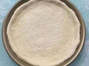 移入不粘披萨盘中，稍微整理一下，使其外边一圈比里面厚。