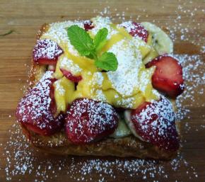 取出烤好的吐司，表面淋蜂蜜，撒适量糖粉，插上薄荷叶装饰。