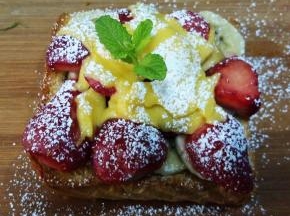 取出烤好的吐司，表面淋蜂蜜，撒适量糖粉，插上薄荷叶装饰。