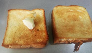 取出烤好的吐司片，趁热抹上层黄油。