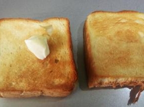 取出烤好的吐司片，趁热抹上层黄油。