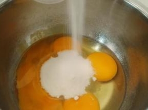 把烤箱预热，上下火170℃，因为做好的面糊容易消泡，所以在磕鸡蛋前就要把烤箱预热好，两个全蛋和两个蛋黄全部打入打蛋盆，再一次性加入所有的糖和盐，搅拌几下，让糖沉到底下，要不待会打发的时候会飞出来