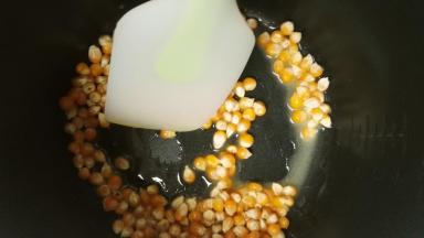 黄油放入电饭锅里，按下煮饭键，将黄油融化，再倒入玉米粒翻拌，让每粒玉米都沾上黄油