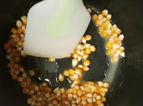 黄油放入电饭锅里，按下煮饭键，将黄油融化，再倒入玉米粒翻拌，让每粒玉米都沾上黄油