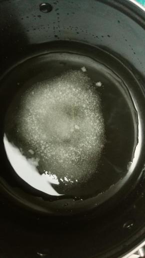 现在来熬焦糖，准备一个大一点的锅，保证爆米花能在里面翻拌就可以，水和糖放入锅里，水没过糖，开中火让它煮沸，记住不要去搅拌它，要不糖浆会返砂，就会变成白色糖粉了