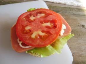 汉堡上挤上番茄酱，放上生菜，午餐肉，再挤上沙拉酱，放上蕃茄片，最后把另一半汉堡片盖上