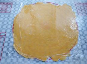 面团取出，上下垫一层保鲜膜，用擀面杖擀成一张大饼皮，要比派盘直径大一圈