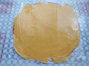 面团取出，上下垫一层保鲜膜，用擀面杖擀成一张大饼皮，要比派盘直径大一圈