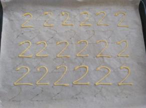 裱花袋上剪一个小口，在油纸上挤出2字的形状，头部稍微大点