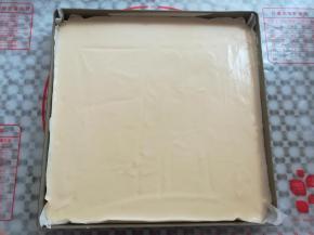 蛋糕糊倒入铺了油纸的烤盘里，依靠面糊的流动性流向四周，高出的蛋糕糊用刮板刮平一点，有大气泡的地方用牙签划一下