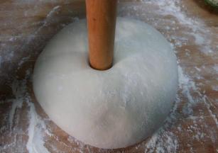 发好的面团，揉搓至面团切面无气孔，收圆。用擀面杖插入面团中间。