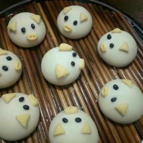 猪耳朵，嘴巴沾少许水固定在馒头上，鼻子用筷子戳出鼻孔，然后拿黑豆当眼睛，可爱的猪猪完成