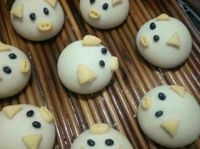 猪耳朵，嘴巴沾少许水固定在馒头上，鼻子用筷子戳出鼻孔，然后拿黑豆当眼睛，可爱的猪猪完成