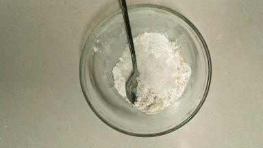 现在来做脆底的沾料，将面粉、白芝麻、白砂糖混合均匀就可以了，在烤盘里倒入玉米油，用刷子刷均匀备用