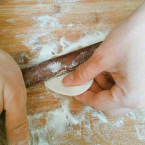 取一个小面剂开始擀皮，左手捏住面剂上方，右手拿擀面杖，左右手配合，左手捏住面剂子，右手往上推擀面杖，推到面片过中间一点往回拉，往回拉擀面杖的同时，左手逆时针转动一下面片，如此循环大约面片转动一周时一个饺子皮就擀好了(一个连贯动作下来大概几秒钟，刚开始做可能有点慢，多做几次熟练了就好了)