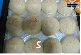 面团发酵至两倍大，表面刷蛋液，撒上芝麻；