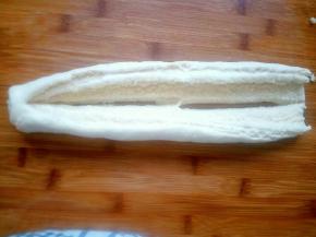 将卷起的圆柱体稍微按扁，竖着切开，注意顶端不要全部切断，翻转90°椰蓉向上