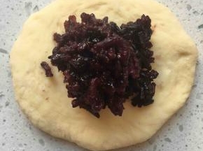 松弛好的面团压扁，包入紫米馅